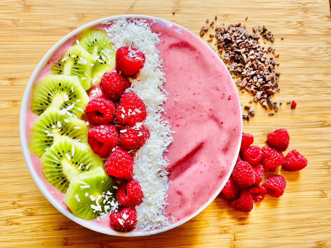 Elderberry smoothie bowl with kiwi, raspberries, coconut, cacao nibs.