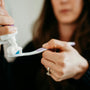 woman putting toothpaste on toothbrush