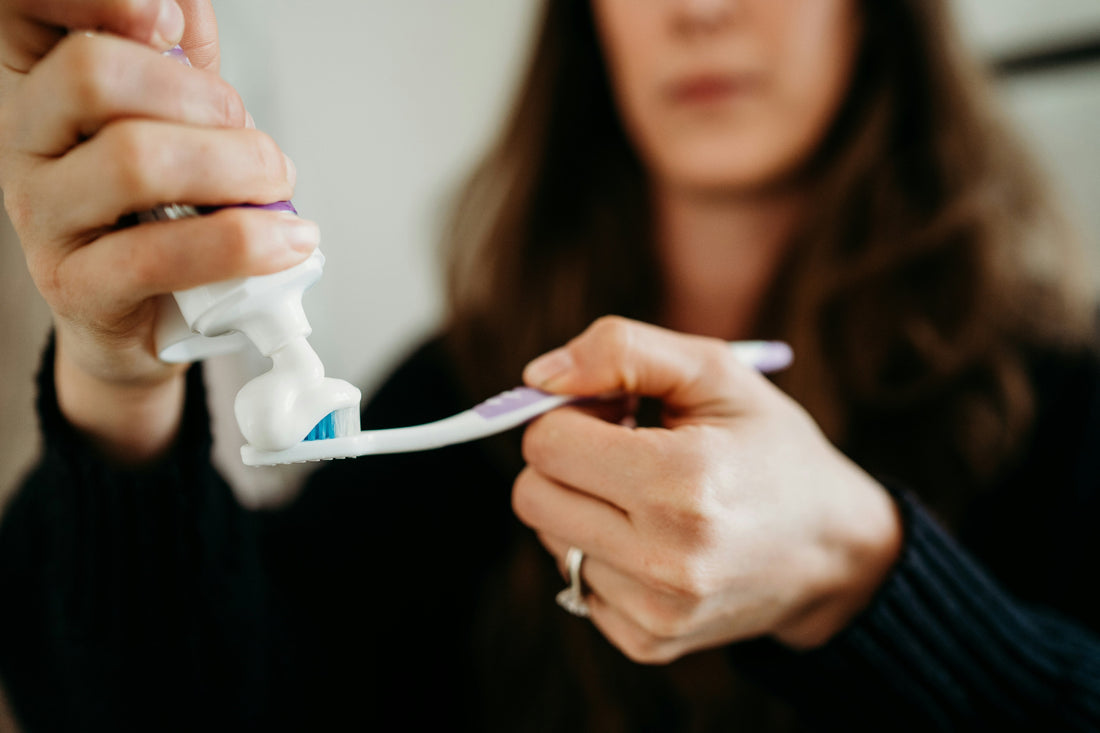 woman putting toothpaste on toothbrush