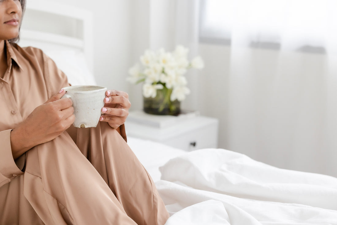 woman sitting on the bed sipping tea for self-care